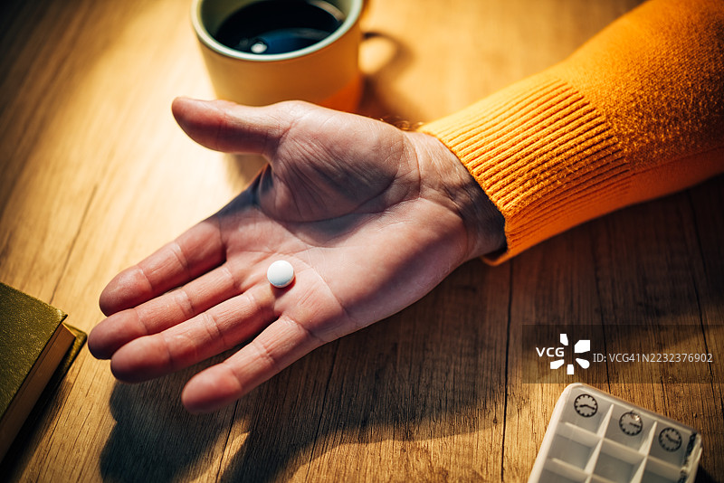 夜晚，老人在家中服药，同时享用温暖的饮品图片素材