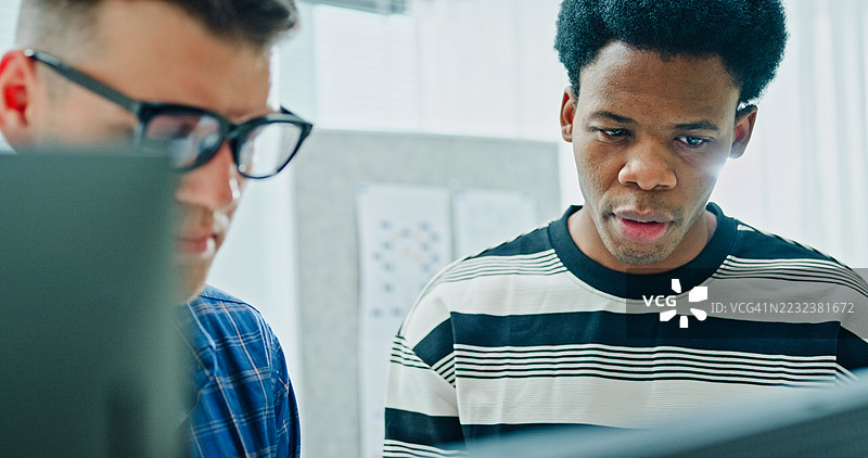 两名男性软件开发人员在办公室会面，多个电脑屏幕上显示着编程代码，他们正在合作项目。人工智能与编程。图片素材