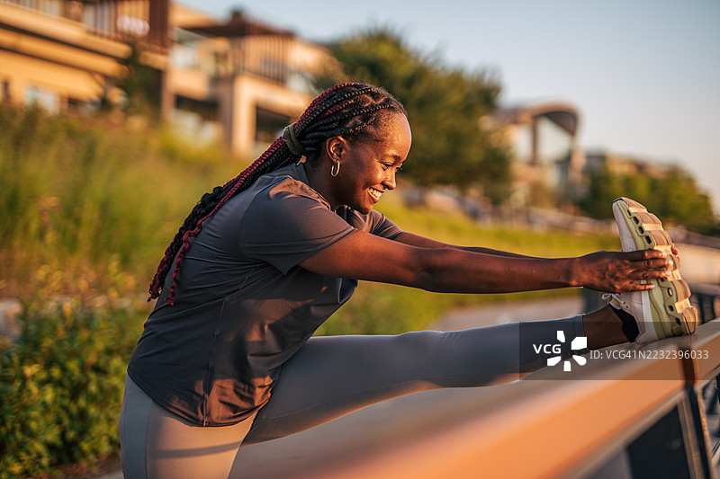 年轻的黑人女性在锻炼后拉伸腿部图片素材