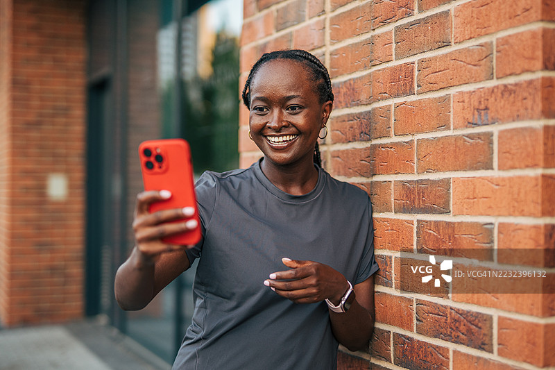 微笑的运动员在锻炼后用智能手机自拍图片素材