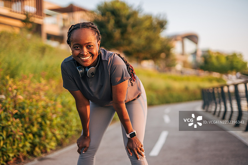 微笑的运动女性在户外锻炼时休息片刻图片素材