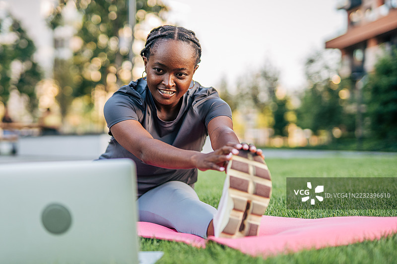 年轻女性在公园参加在线健身课程图片素材