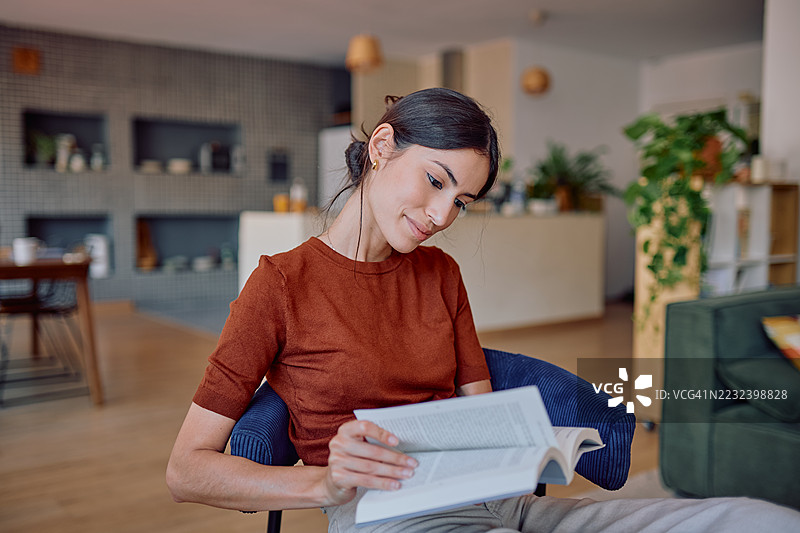 年轻女性在家中阅读一本书图片素材