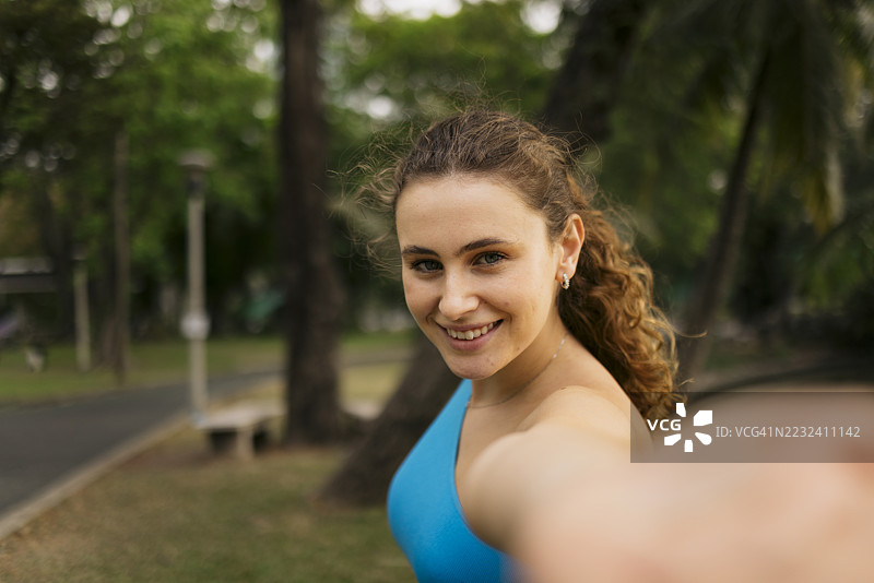 微笑的女运动员在公园里自拍图片素材