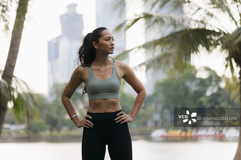 坚定的女运动员在热带公园中双手叉腰摆姿势图片素材