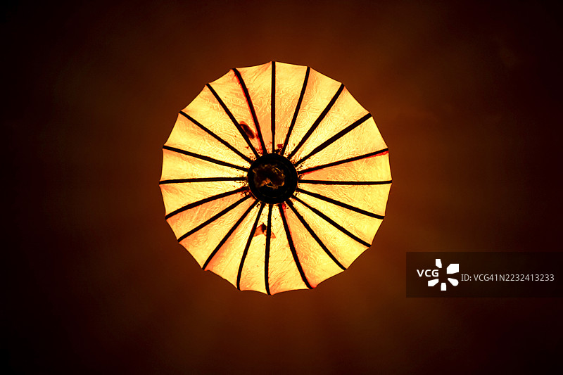 夜晚，黄色丝绸灯笼高挂在锈红色的天花板上图片素材