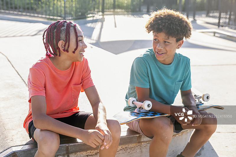 初中男孩在滑板公园走动并交谈图片素材