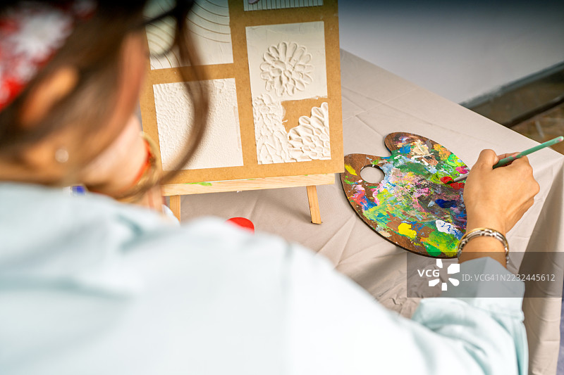 艺术家在她的工作室里从调色板上取颜料图片素材