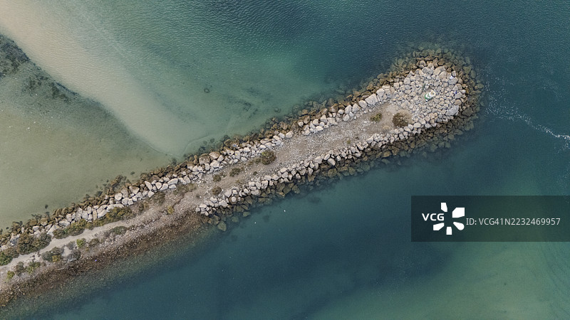 海岸岩石形成的俯视图，海洋灯塔被清澈的海水环绕，附近有沙滩。图片素材