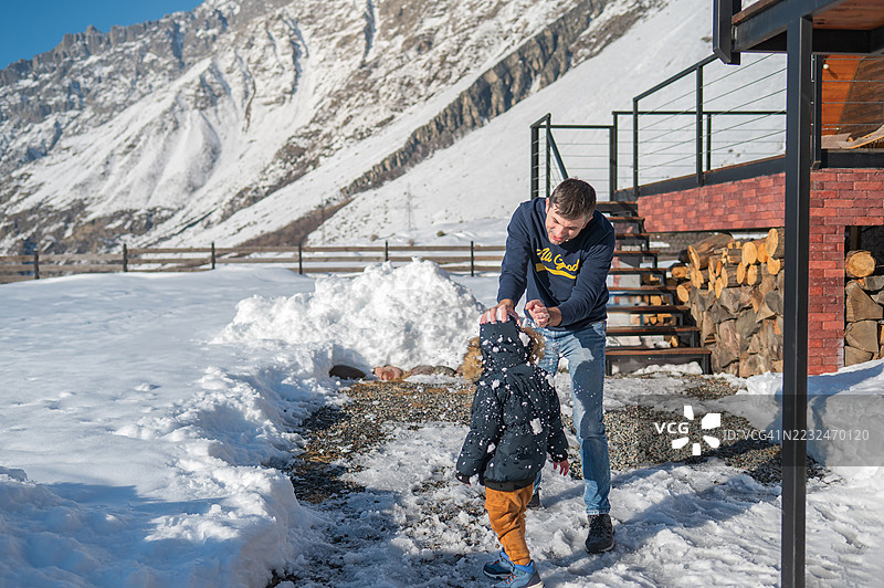 父亲和儿子在美丽的山景中享受雪天，玩雪仗。图片素材
