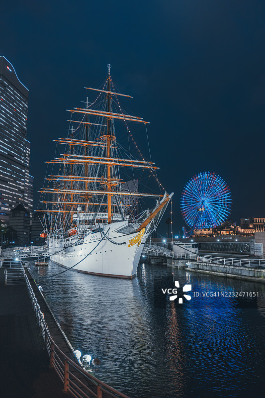历史悠久的高大帆船在夜间停泊，背景是亮起的摩天轮，横滨，神奈川县，日本图片素材