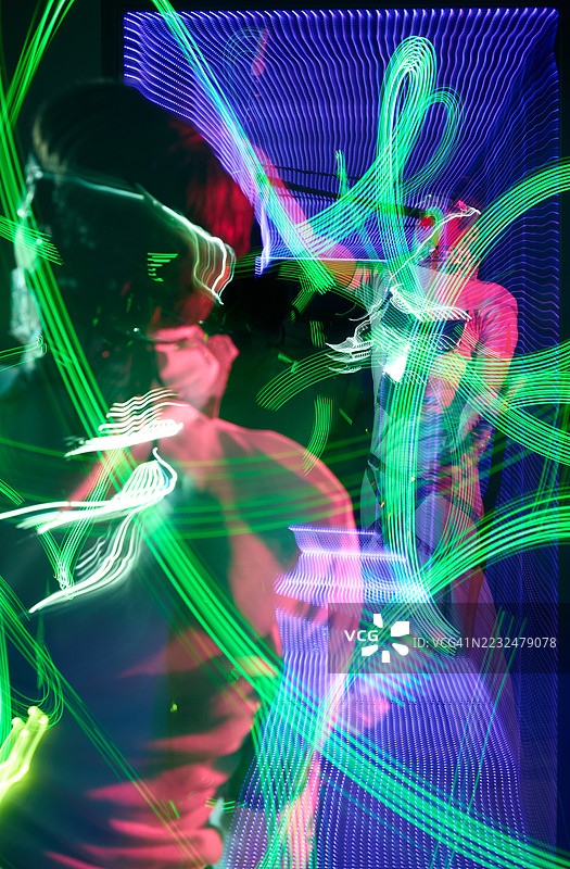 年轻男性表演者使用LED波光灯在镜子中展示光影图案图片素材