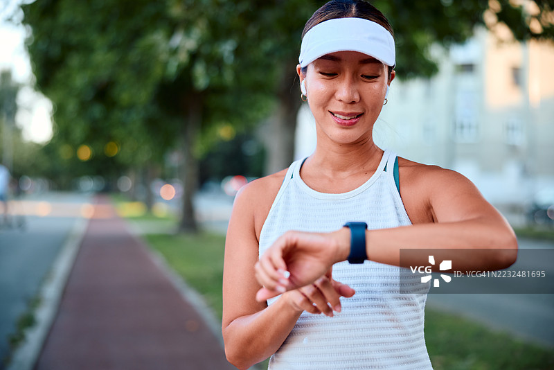 年轻女运动员在晨跑时查看智能手表上的表现图片素材