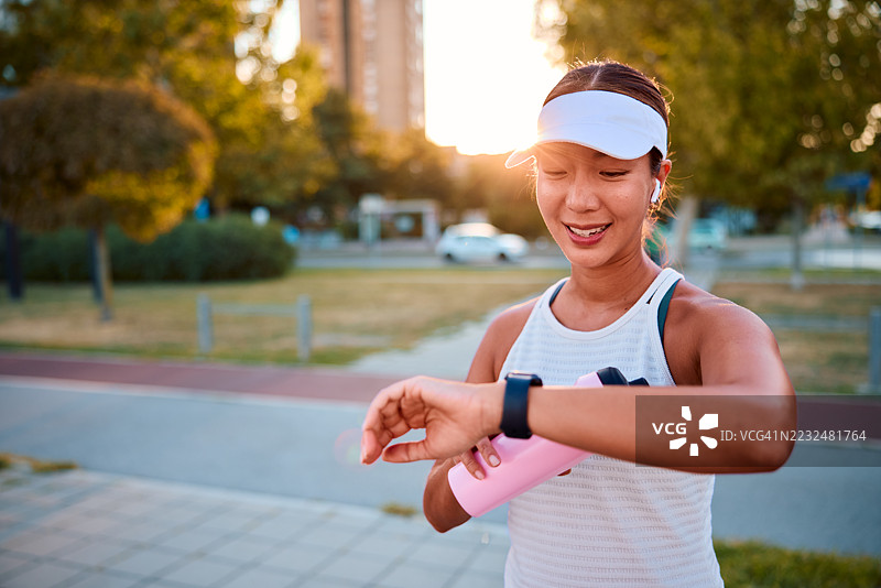 年轻女运动员在训练后查看智能手表上的表现图片素材