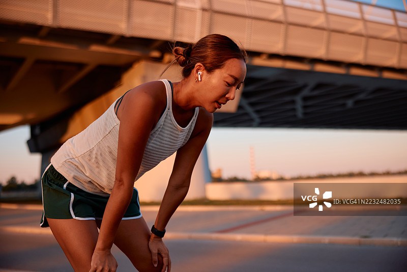 疲惫的女运动员在桥下休息，刚完成跑步训练图片素材