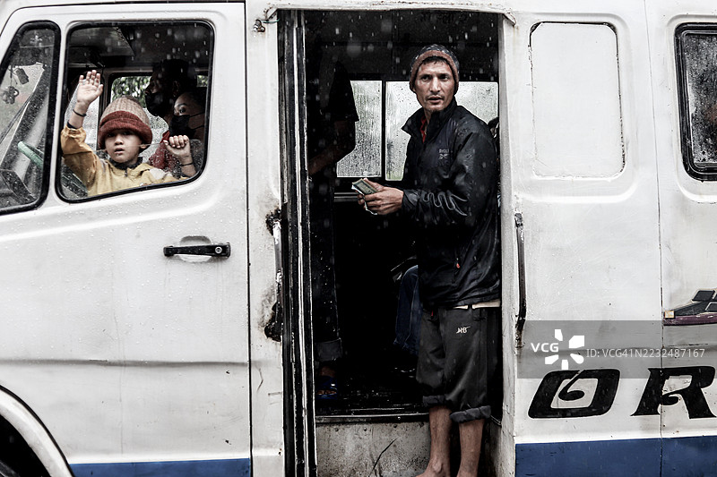 下雨天的一辆本地公交车，一个小孩和一位售票员。图片素材