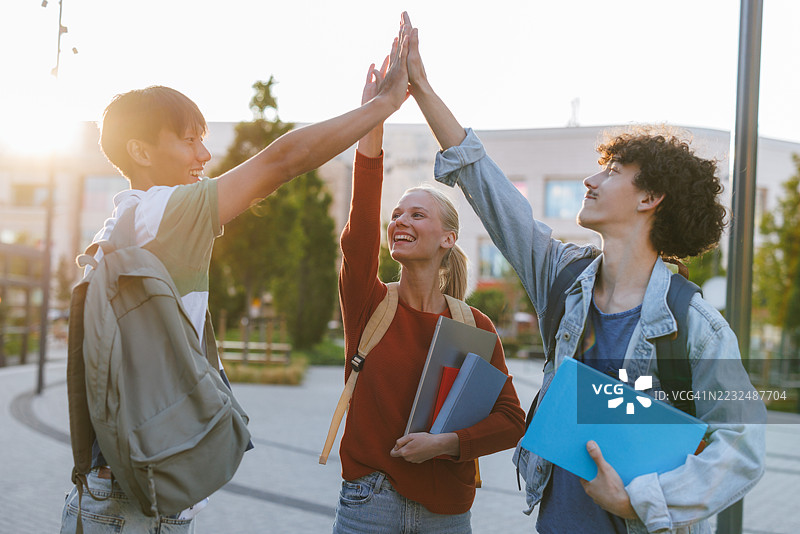 一群快乐的学生在校园户外击掌庆祝图片素材