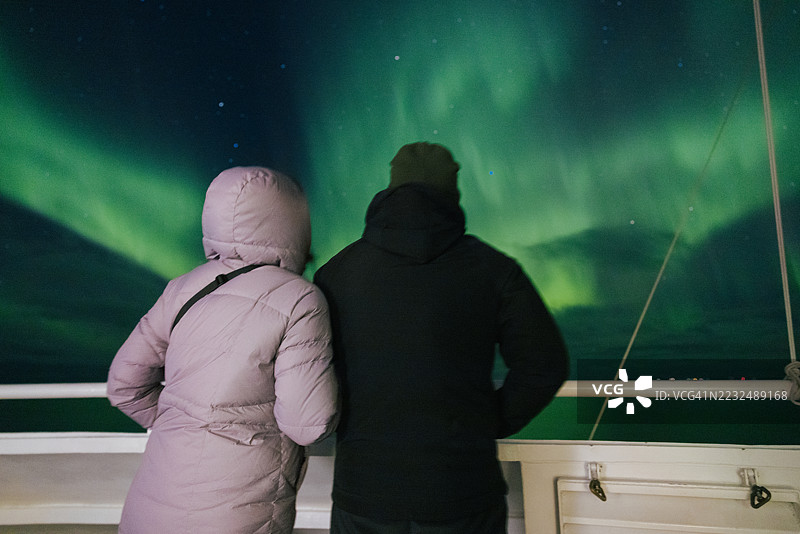 两个人在游轮上欣赏壮丽的北极光图片素材