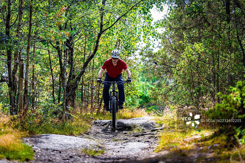 男人骑车跳过岩石，专注于地面图片素材
