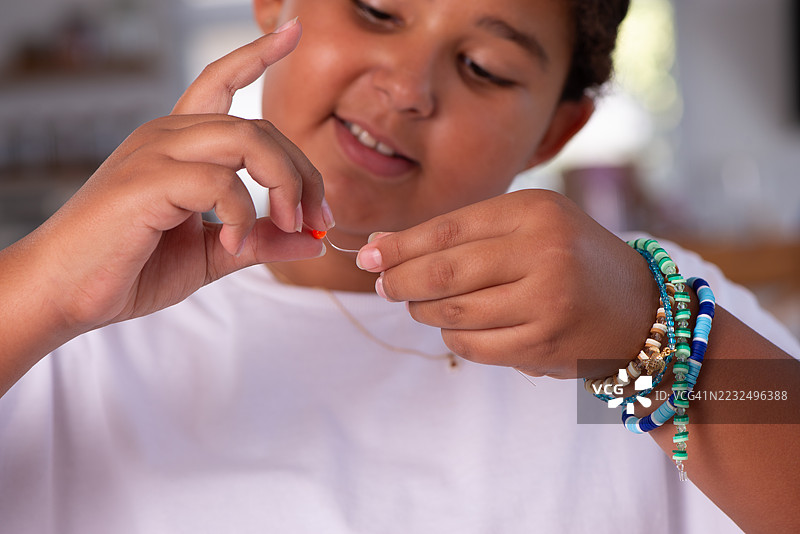 孩子在串珠制作手工首饰。图片素材
