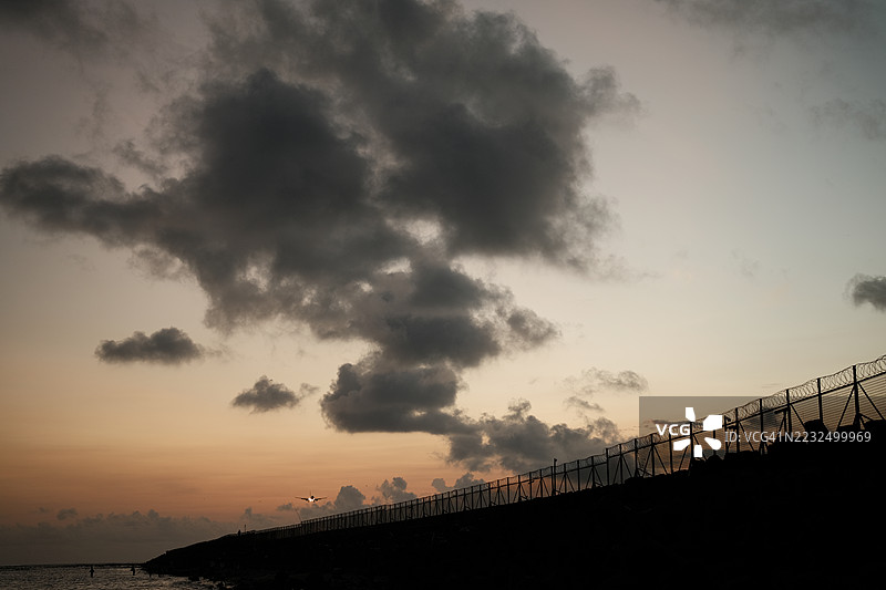 带刺铁丝网。监狱或边境围栏，带有剃刀丝，背景为日落天空。安全概念图片素材