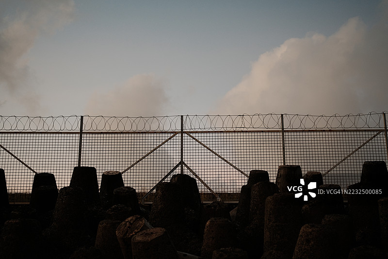 带刺铁丝网。监狱或边境围栏，带剃刀丝，夕阳天空背景。安全概念图片素材