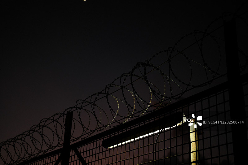 铁丝网围栏。监狱或边境围栏，带有剃刀丝，背景是日落天空。安全概念图片素材