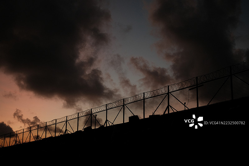 铁丝网围栏。监狱或边境围栏，带有剃刀丝，背景是日落天空。安全概念图片素材