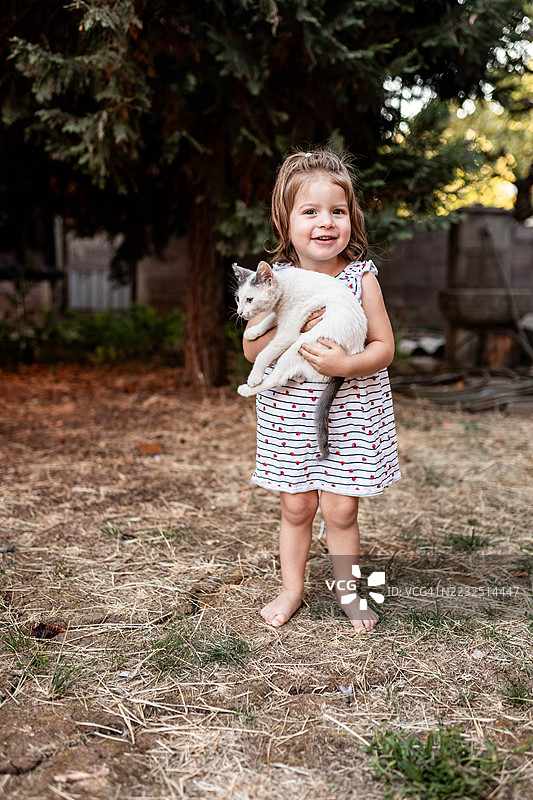孩子在乡村环境中拥抱可爱的小猫图片素材