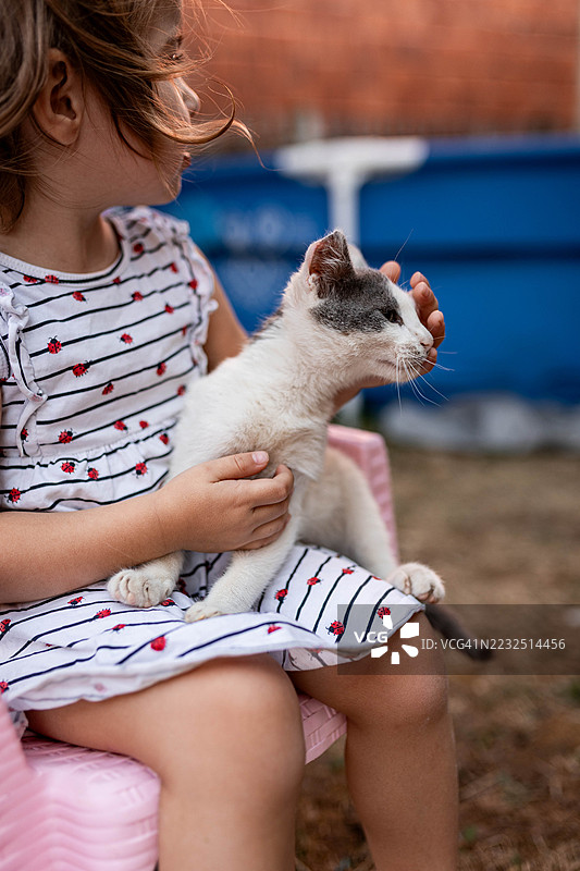 孩子坐在塑料椅子上抱着小猫咪图片素材