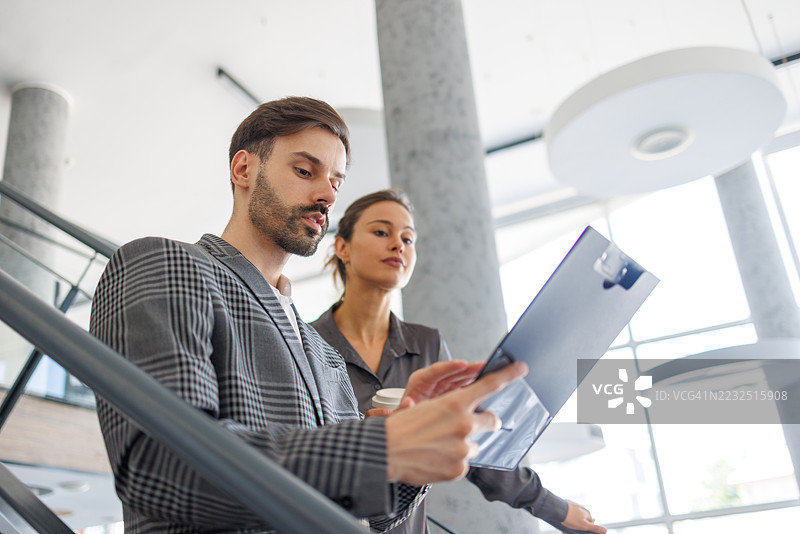 商务同事在办公室楼梯上讨论文件图片素材