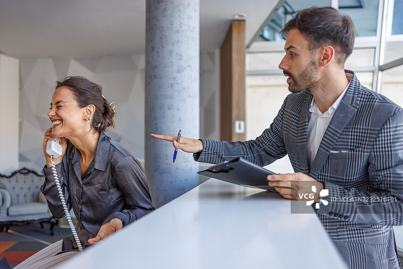 经理指着一名在电话中大笑的员工图片素材