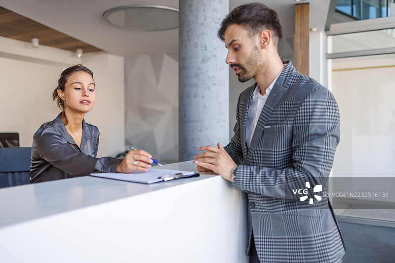 酒店接待员帮助商务人士填写入住登记表图片素材