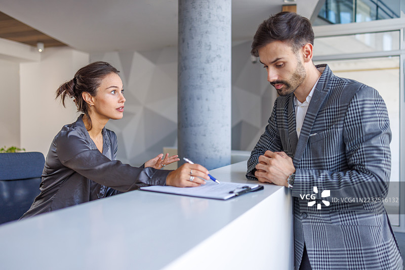 酒店接待员协助商务人士办理入住手续图片素材