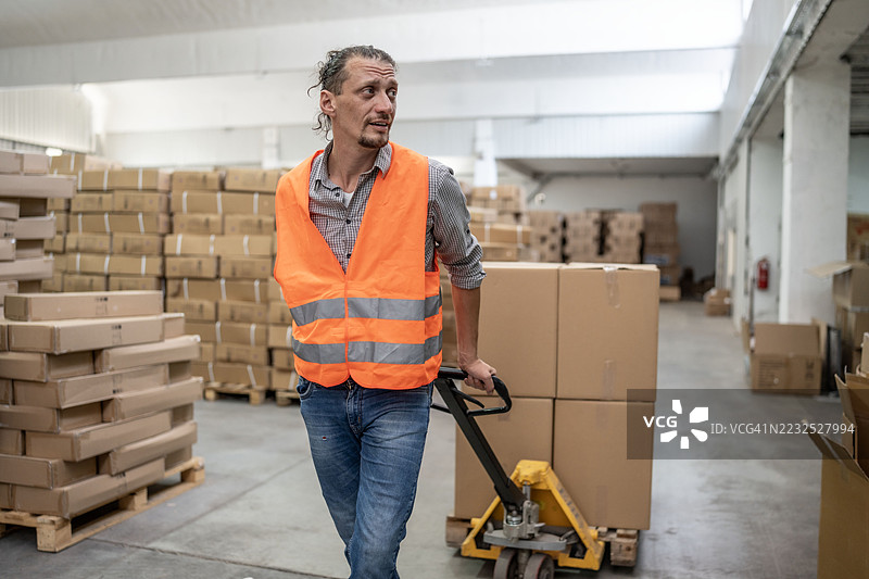 工业仓库中的工人使用托盘车搬运物品图片素材