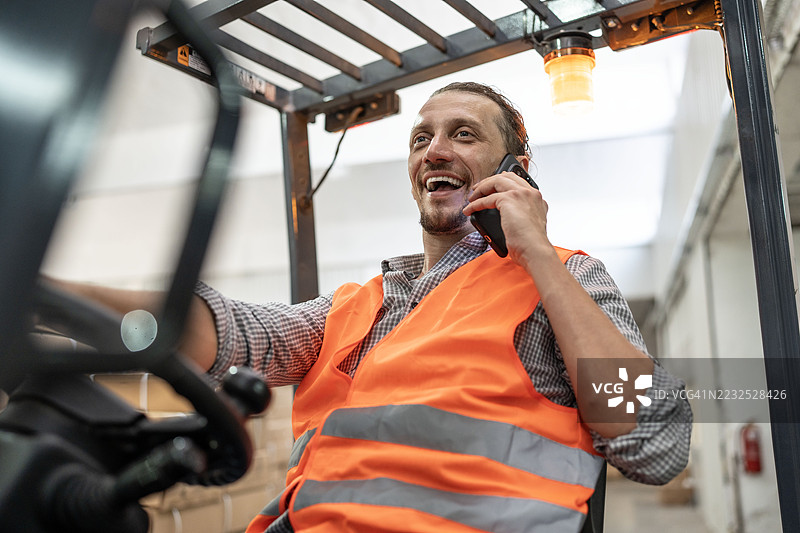 在仓库中使用叉车并打电话的工人图片素材