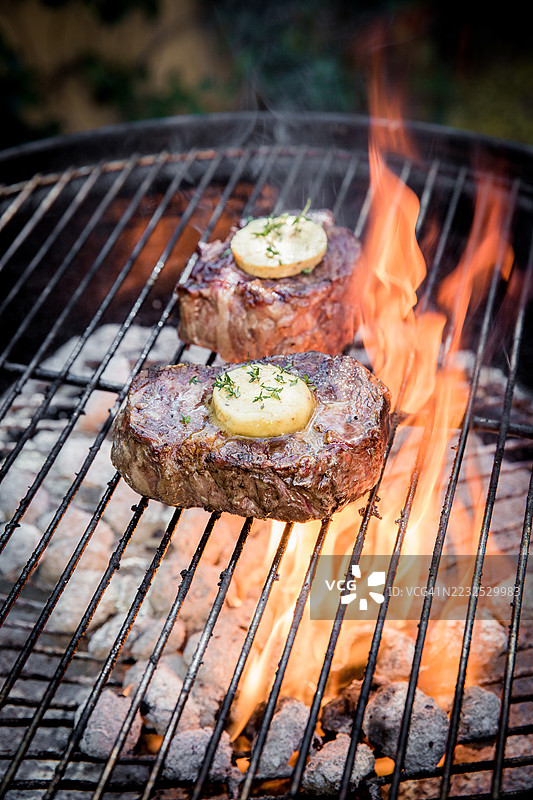 多汁的牛排在明火上烤制，搭配香草黄油图片素材