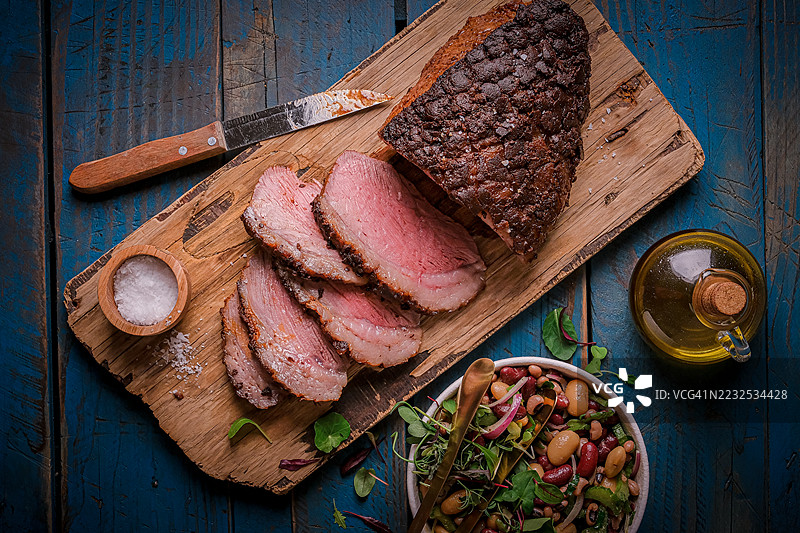 美味的切片烤牛肉配沙拉，盛放在木质托盘上图片素材