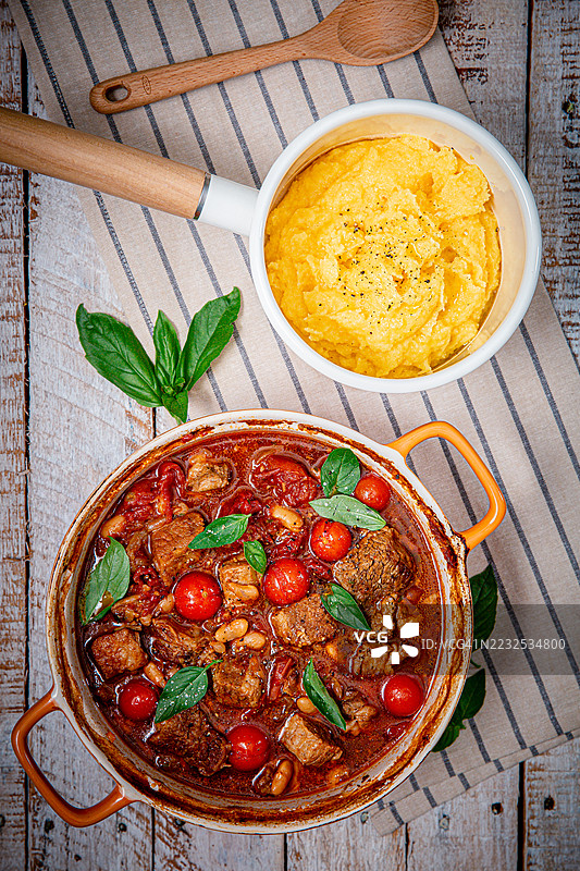 美味的玉米粥炖菜，配有樱桃番茄和香草，摆放在乡村风格的餐桌上图片素材