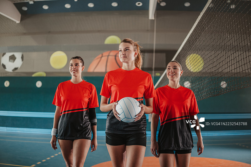 年轻女性在充满活力的室内排球比赛中展现团队合作与技巧，背景充满活力图片素材