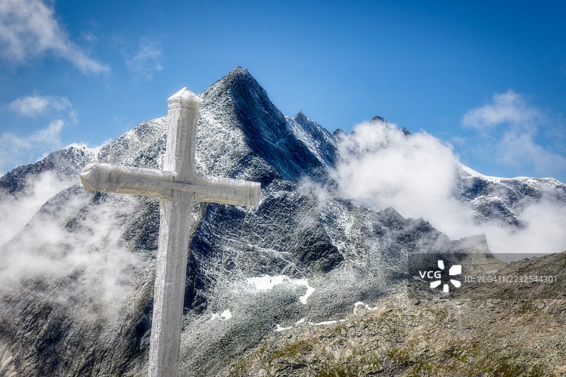雪山之巅，晴朗的蓝天下，一座十字架矗立在雪地里，法国奥苏瓦图片素材