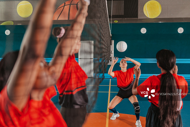 年轻女性在健身房进行激烈的排球训练，展现团队合作与运动能力图片素材