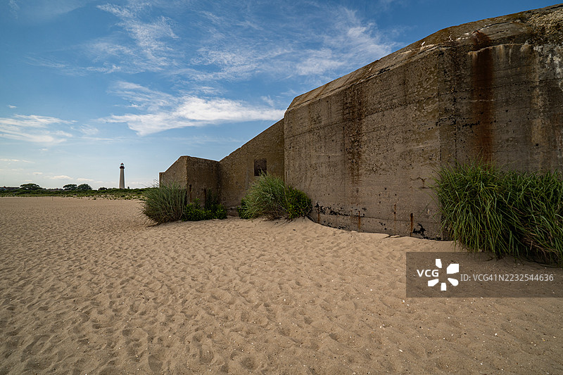 沙滩上的废弃碉堡与远处的灯塔，梅角，美国图片素材