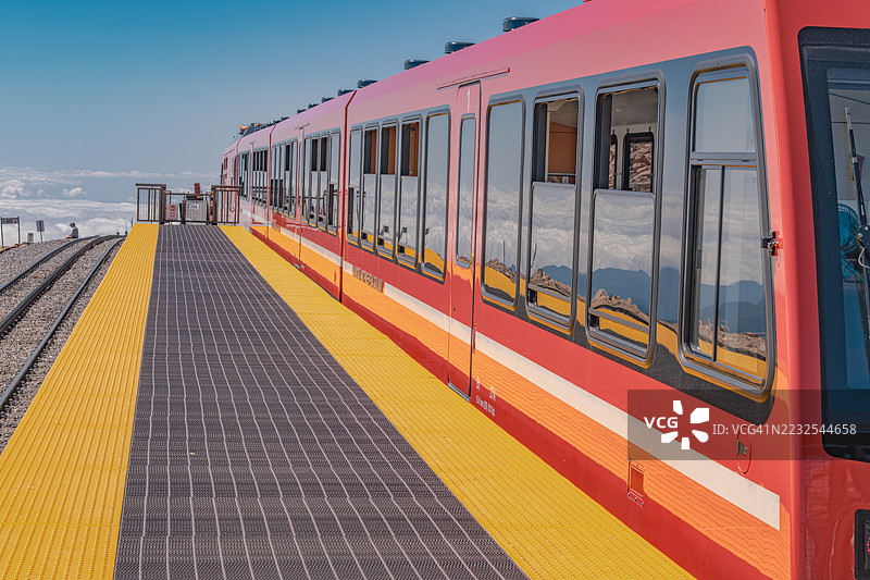 红色的火车停靠在山间铁路站台，背景是风景如画的美景图片素材