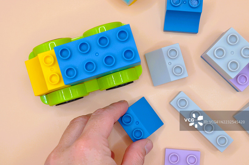 手上玩着桌上的彩色积木图片素材