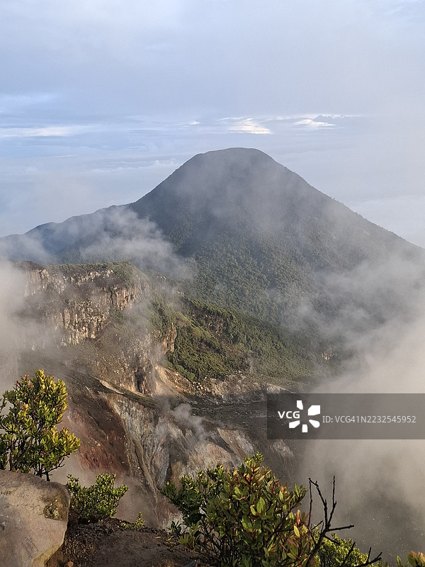雾气弥漫的火山景观与郁郁葱葱的植被图片素材