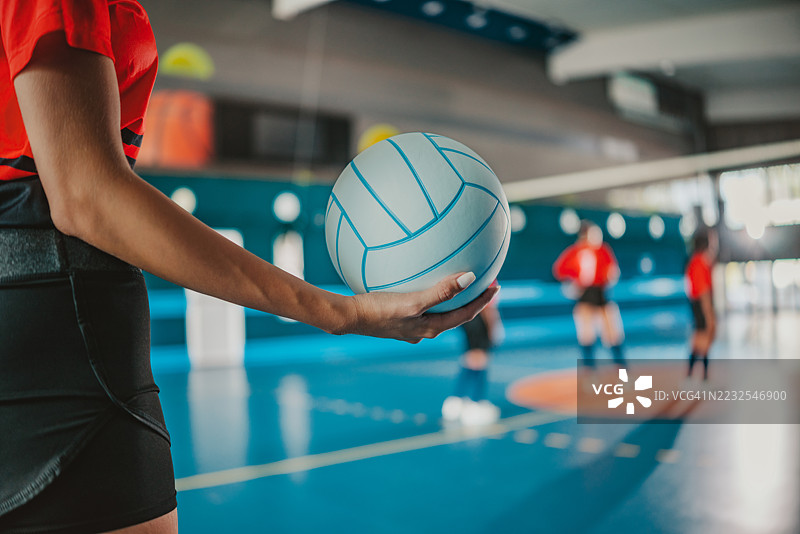 年轻女性在室内球场进行激烈的排球比赛，展现出团队合作和运动能力图片素材