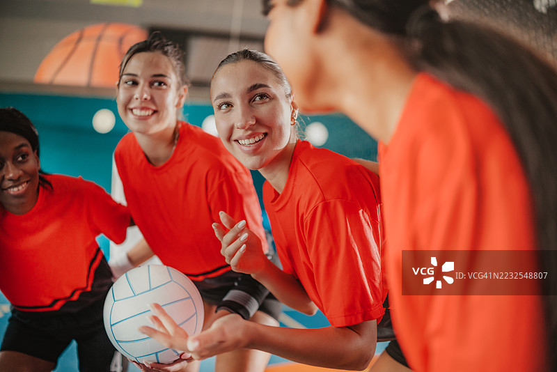 年轻女性们在室内为排球比赛做准备，激动人心的时刻，展现了团队合作与运动活力图片素材