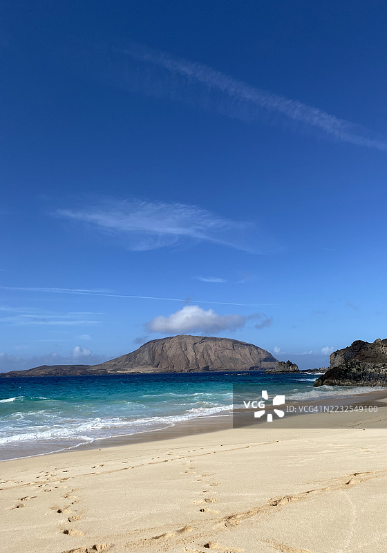 阿罗纳，西班牙的宁静海滩，湛蓝的天空和岩石岛屿图片素材