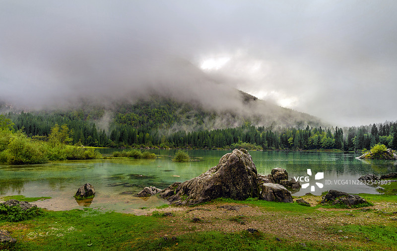意大利塔尔维西奥的雾气弥漫的山湖与森林倒影图片素材